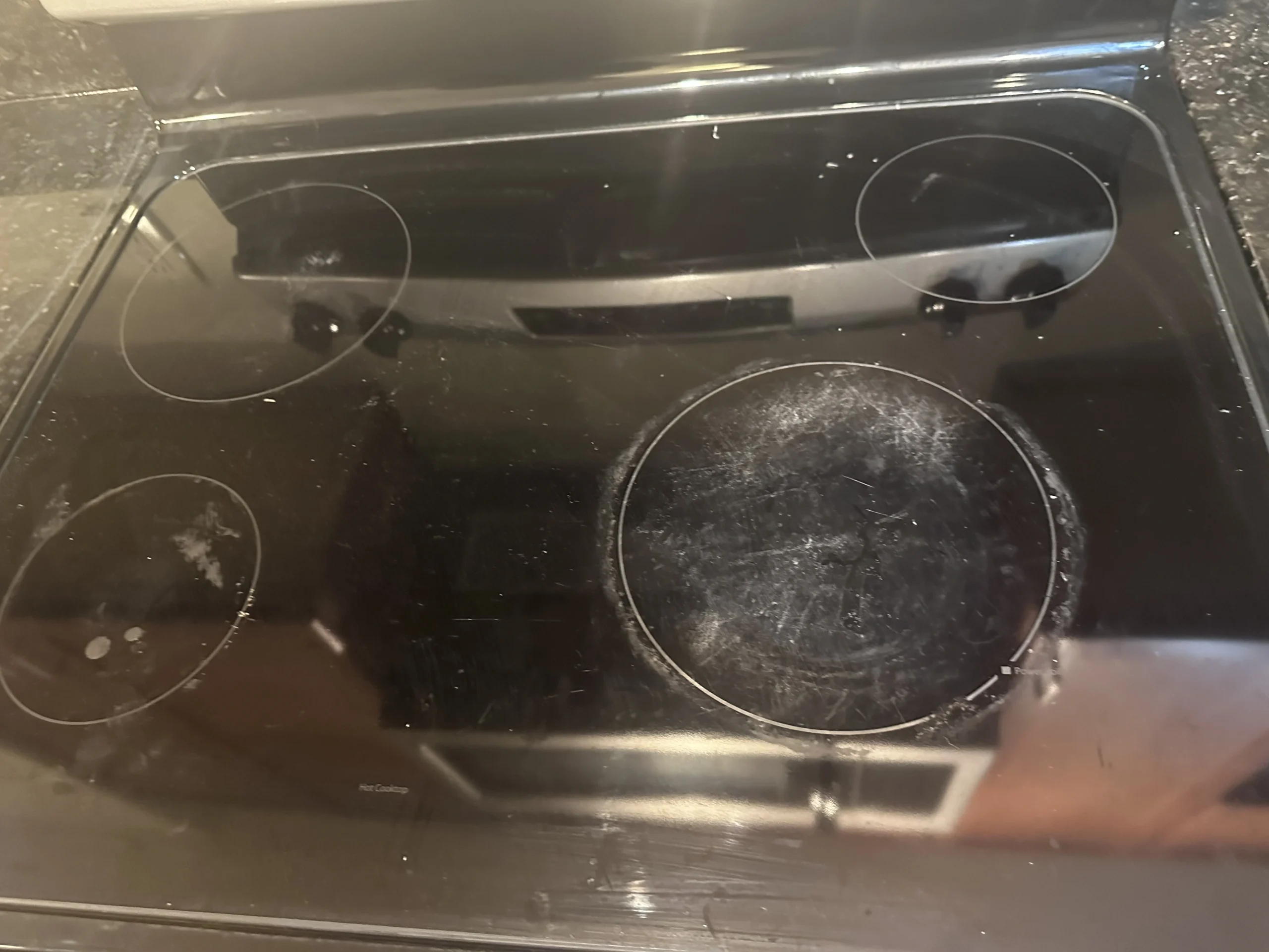 Before: a glass cooktop with heavy burned-on residue at move-out